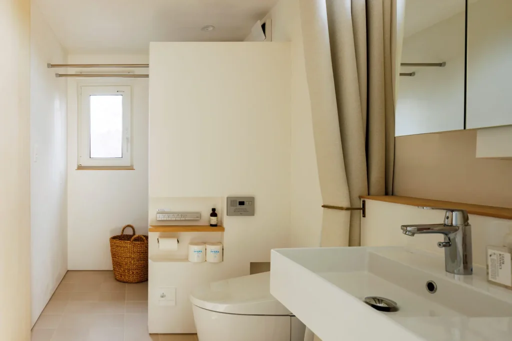 水まわりは間仕切りなくつながる。トイレの奥は洗濯室。洗濯機やボイラーが見えないよう壁の高さや位置にこだわった